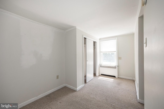 corridor with ornamental molding, radiator, and light carpet