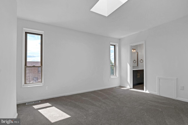 carpeted empty room featuring a skylight