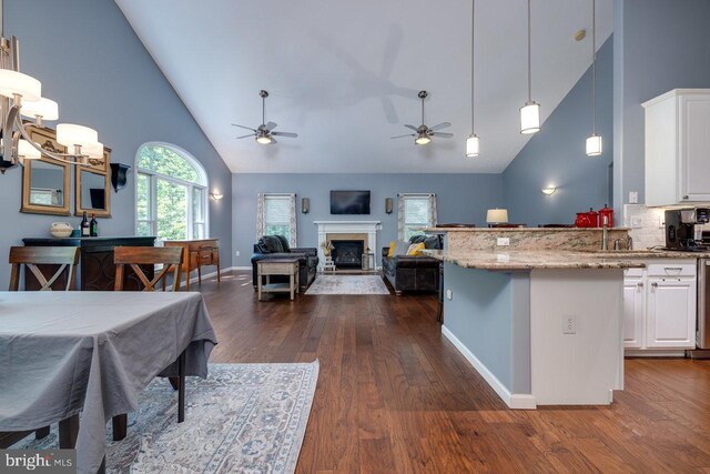 kitchen with ceiling fan, dark hardwood / wood-style flooring, white cabinets, high vaulted ceiling, and light stone countertops