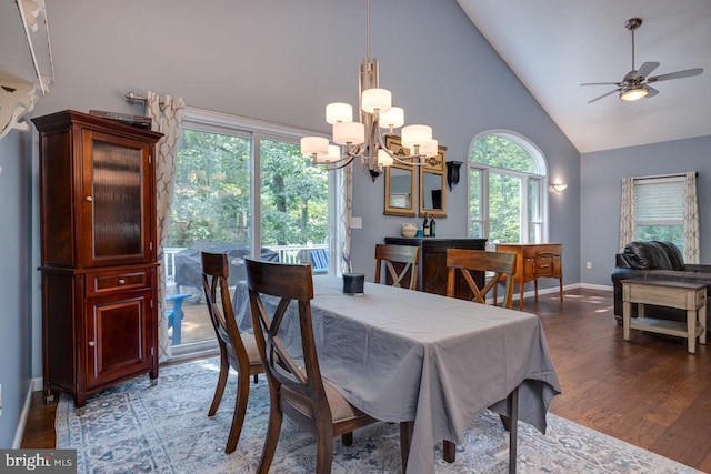 dining room with high vaulted ceiling, ceiling fan with notable chandelier, and hardwood / wood-style floors