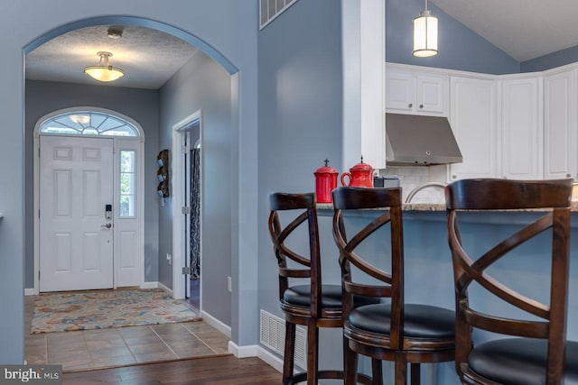 entrance foyer featuring lofted ceiling, hardwood / wood-style floors, and a textured ceiling