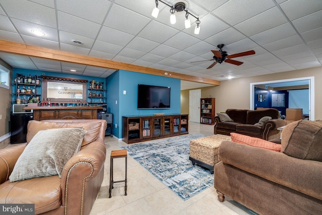 tiled living room featuring a drop ceiling, rail lighting, bar area, and ceiling fan