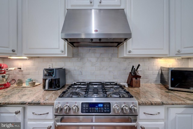 kitchen featuring wall chimney range hood, white cabinetry, stainless steel appliances, and backsplash