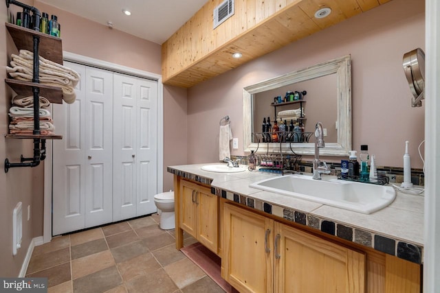 bathroom with toilet, tile patterned flooring, and double vanity