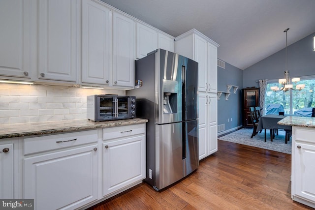 kitchen featuring white cabinetry, backsplash, hanging light fixtures, hardwood / wood-style flooring, and stainless steel fridge