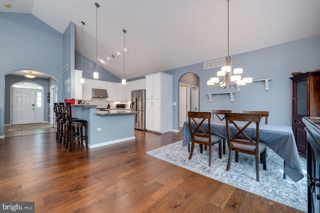 dining room featuring a notable chandelier, high vaulted ceiling, and hardwood / wood-style floors