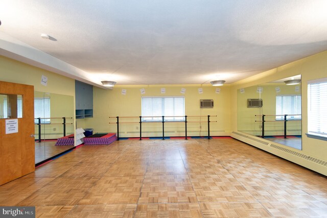 exercise room featuring a wall mounted air conditioner, parquet flooring, and a baseboard heating unit