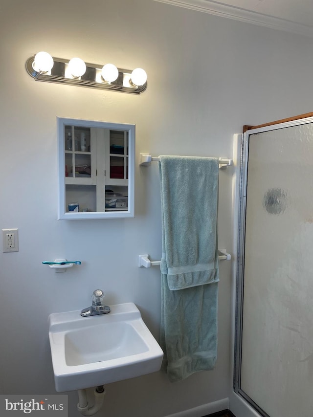 bathroom with ornamental molding, sink, and walk in shower