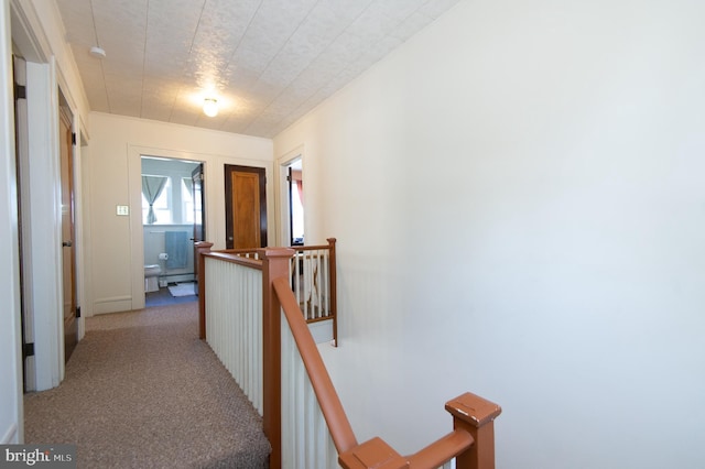 hall featuring light colored carpet and baseboard heating