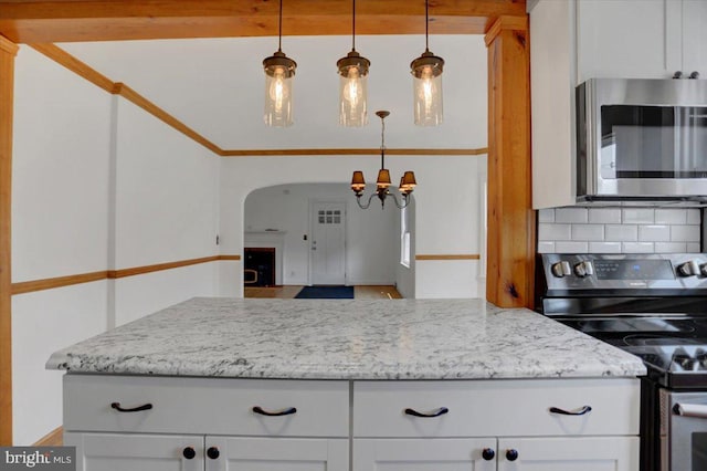 kitchen featuring tasteful backsplash, pendant lighting, stainless steel appliances, white cabinets, and light stone counters