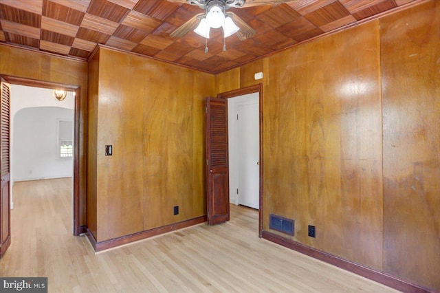 spare room featuring ceiling fan, light wood-type flooring, wood ceiling, and wooden walls