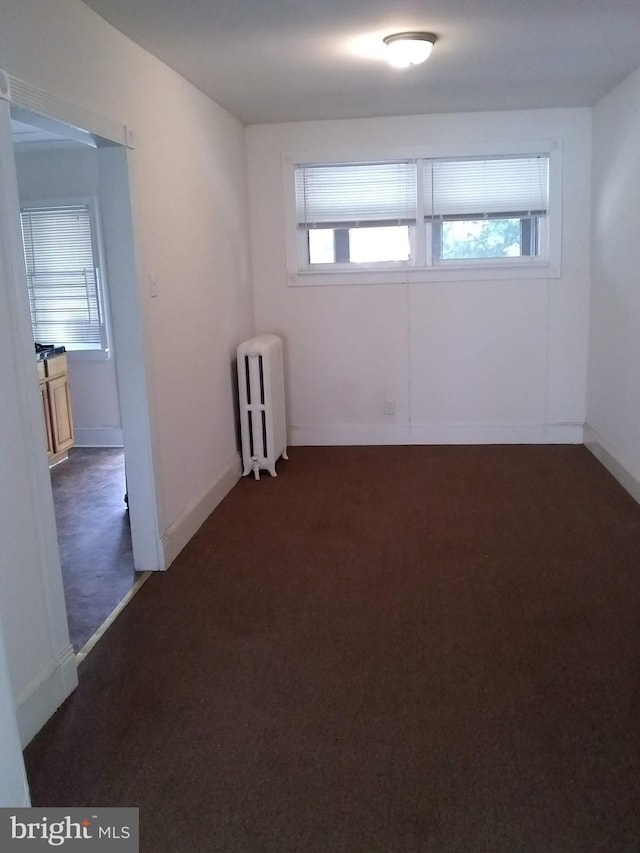 unfurnished room with dark carpet and radiator