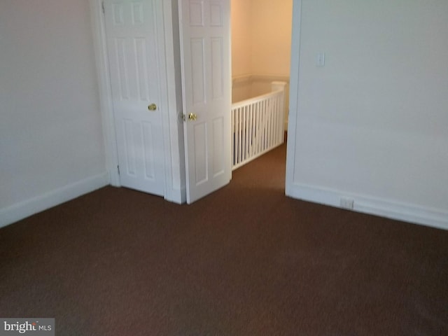 unfurnished bedroom with a closet and dark carpet