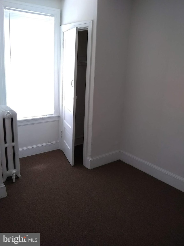 unfurnished bedroom with carpet, a closet, and radiator heating unit