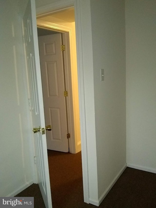 hall with dark colored carpet