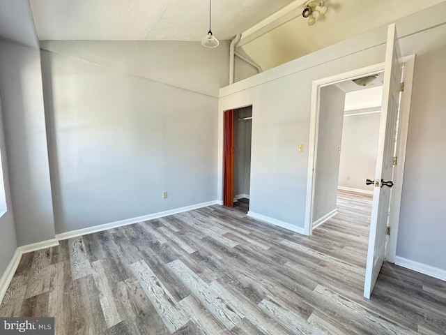 unfurnished bedroom featuring a closet, wood-type flooring, and vaulted ceiling