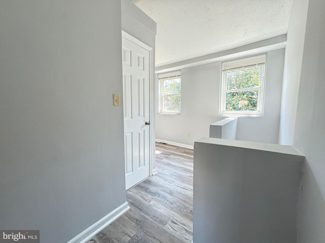 hallway with light hardwood / wood-style floors and a textured ceiling