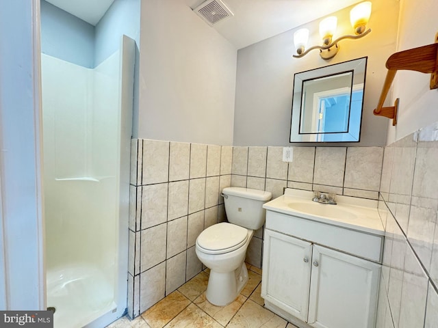 bathroom with tile patterned floors, vanity, a shower, tile walls, and toilet