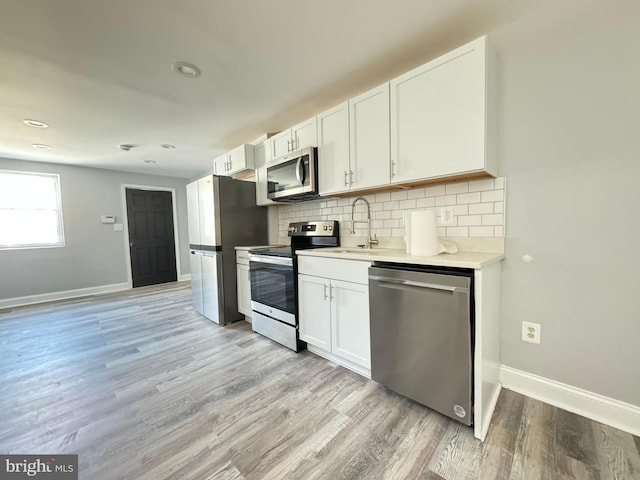 kitchen with sink, tasteful backsplash, light hardwood / wood-style floors, white cabinetry, and stainless steel appliances