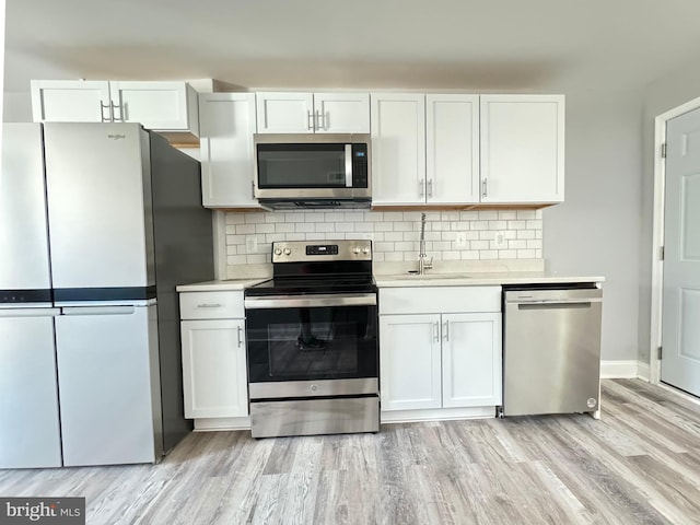 kitchen with white cabinets, stainless steel appliances, light hardwood / wood-style flooring, and tasteful backsplash