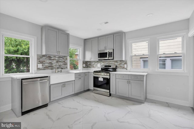 kitchen featuring backsplash, a healthy amount of sunlight, appliances with stainless steel finishes, and light tile patterned floors