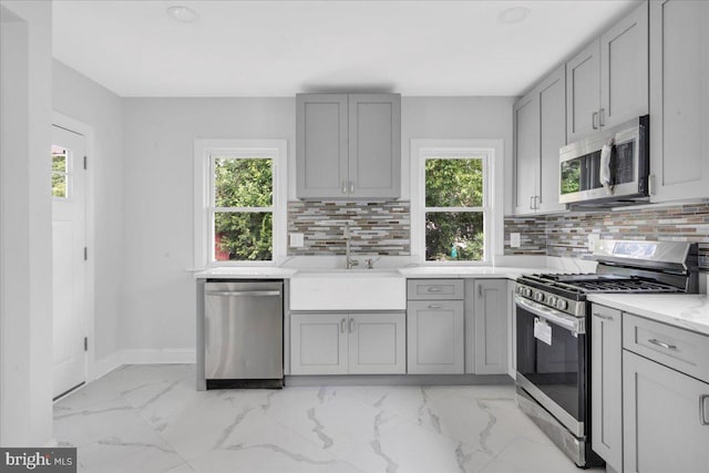 kitchen featuring sink, light tile patterned floors, backsplash, and stainless steel appliances