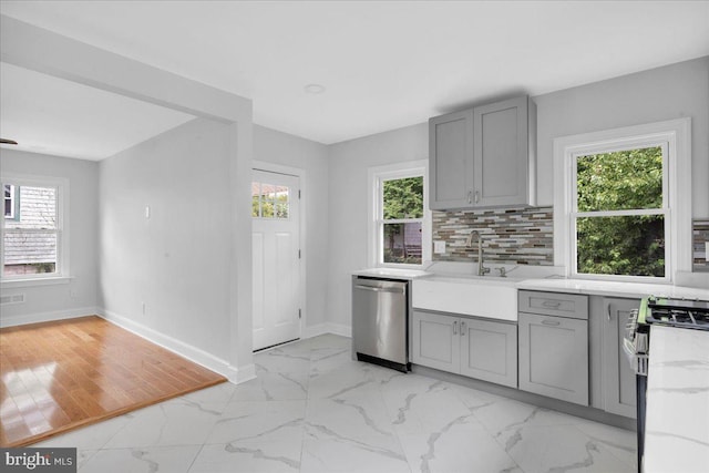 kitchen with stainless steel appliances, light wood-type flooring, sink, backsplash, and gray cabinetry