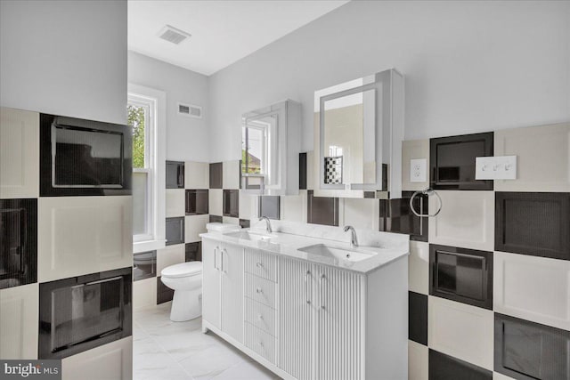 bathroom with dual vanity, toilet, and tile patterned flooring