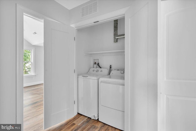 laundry room with washing machine and dryer and wood-type flooring