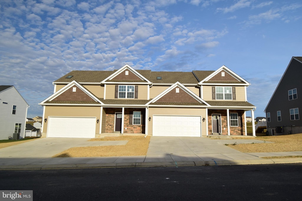 craftsman-style house with stone siding, covered porch, concrete driveway, and an attached garage