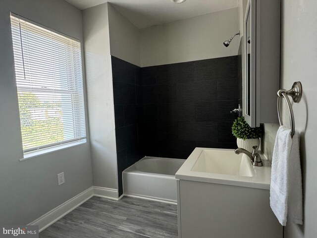 bathroom with tiled shower / bath combo, hardwood / wood-style flooring, and vanity