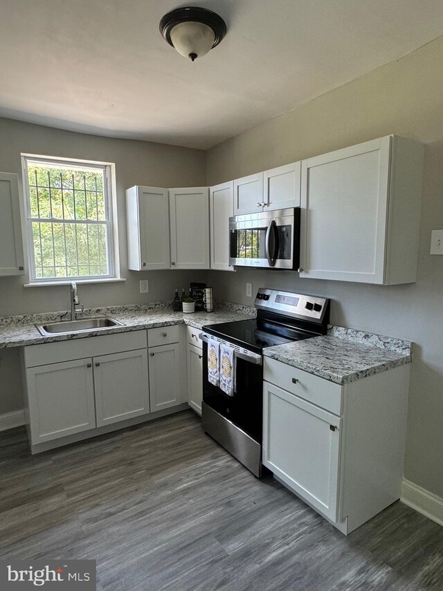 kitchen with sink, white cabinetry, hardwood / wood-style floors, and stainless steel appliances