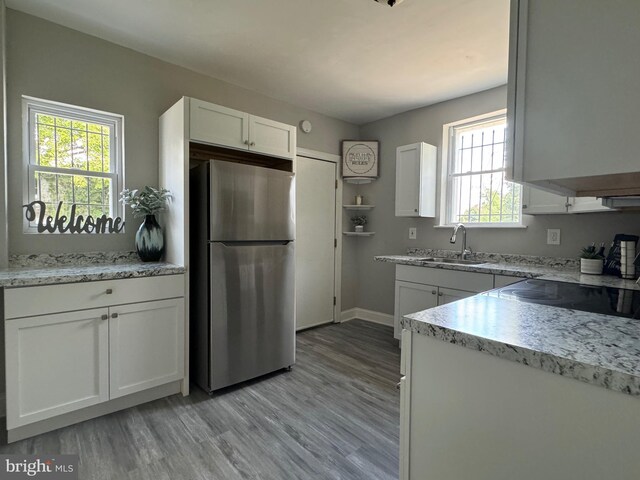 kitchen featuring sink, stainless steel fridge, white cabinets, and light wood-type flooring