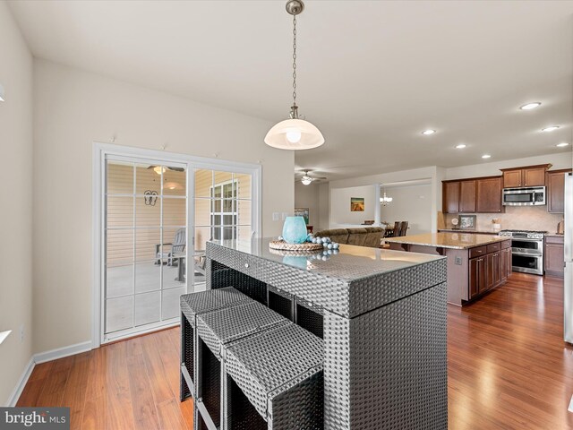 kitchen featuring dark hardwood / wood-style flooring, a center island, stainless steel appliances, and decorative light fixtures