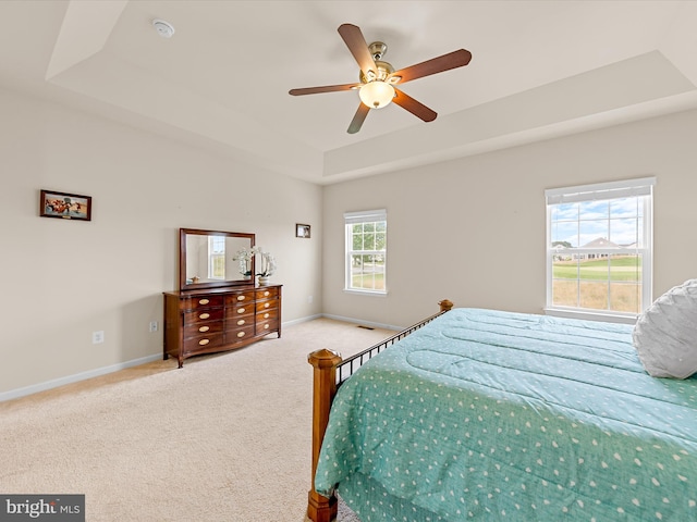 bedroom featuring carpet, ceiling fan, a raised ceiling, and multiple windows