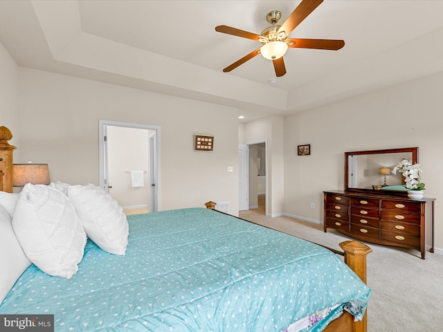 carpeted bedroom with ceiling fan, ensuite bathroom, and a tray ceiling