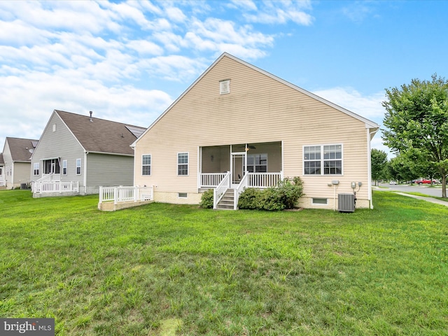 rear view of property with central AC unit and a lawn