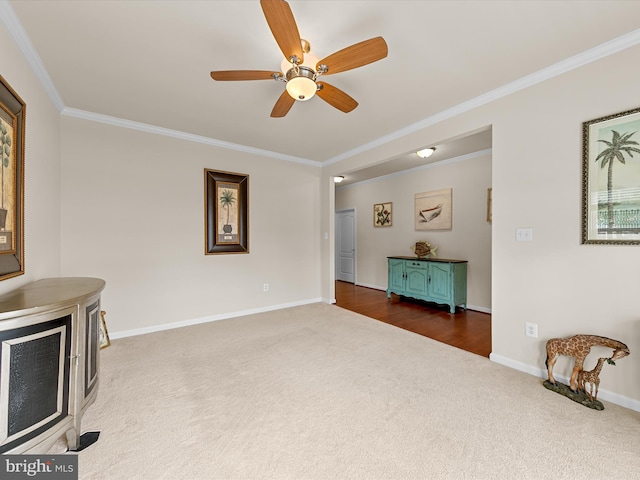 carpeted living room with crown molding and ceiling fan