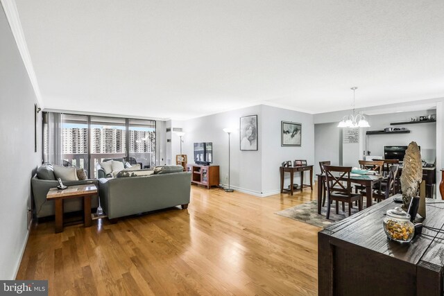 living room featuring crown molding, light hardwood / wood-style flooring, and a notable chandelier