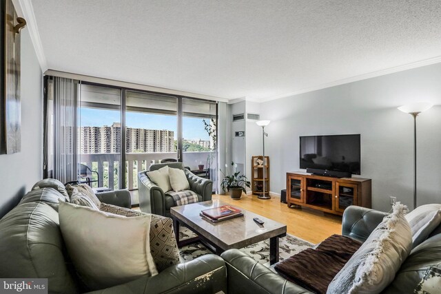 living room featuring a textured ceiling, hardwood / wood-style flooring, ornamental molding, and floor to ceiling windows