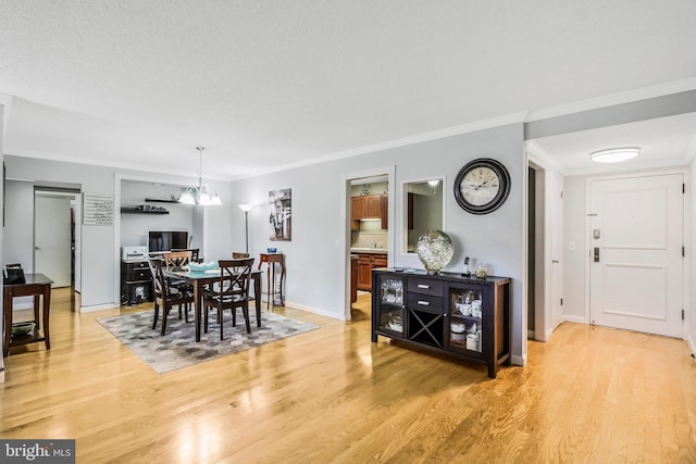 dining area featuring light hardwood / wood-style floors, ornamental molding, and an inviting chandelier