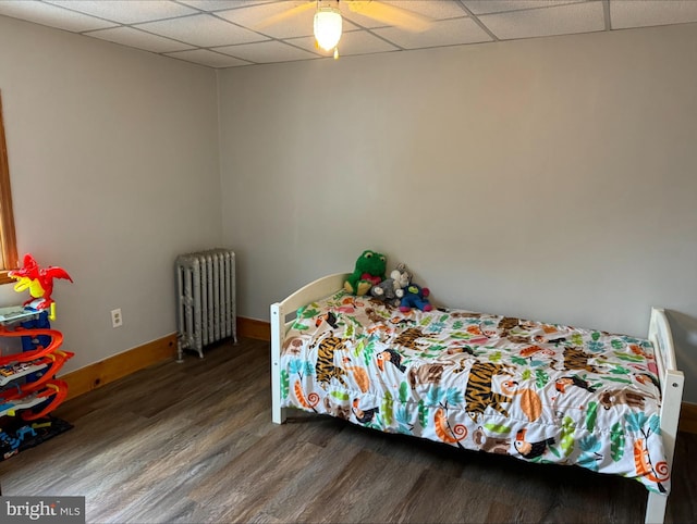 bedroom with ceiling fan, a paneled ceiling, hardwood / wood-style floors, and radiator heating unit