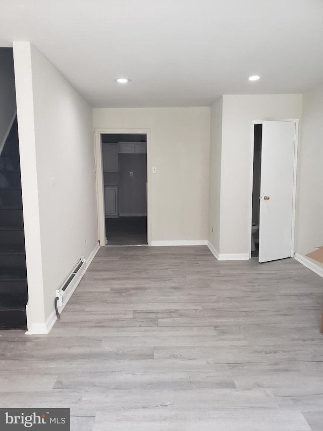 empty room with light hardwood / wood-style floors and a baseboard heating unit