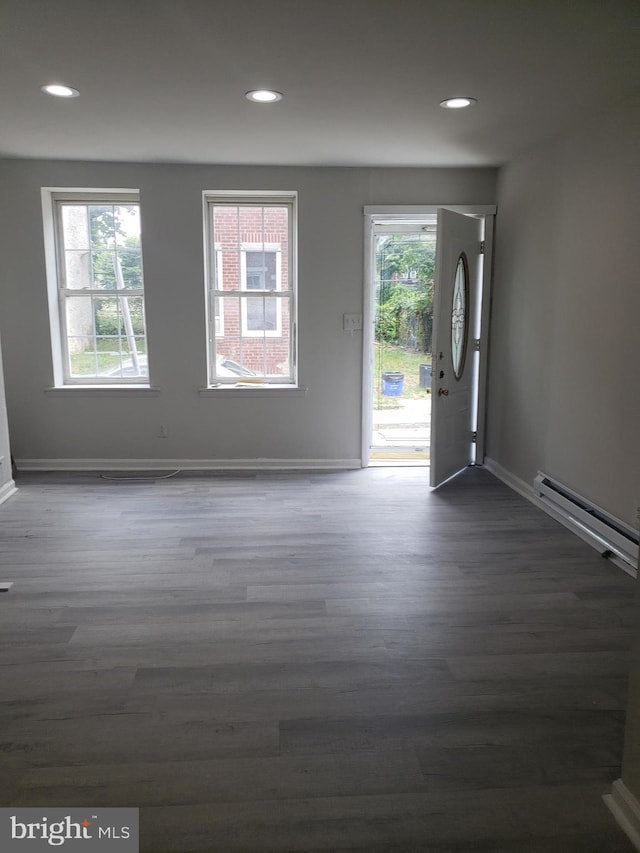 empty room featuring a wealth of natural light, dark hardwood / wood-style flooring, and baseboard heating