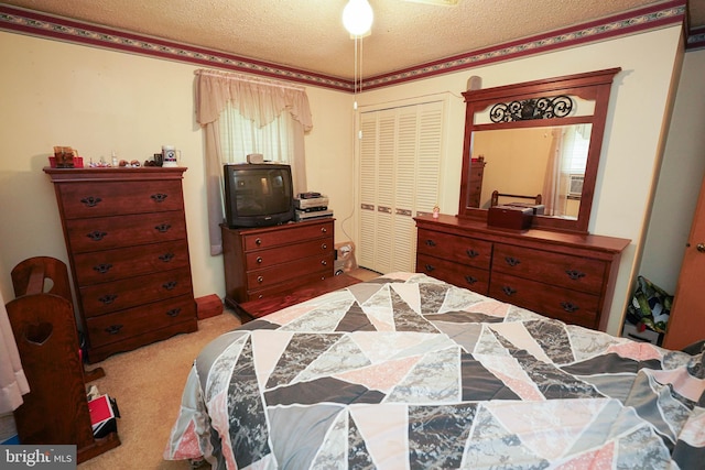 bedroom with a closet, light colored carpet, and a textured ceiling