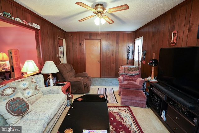 living room featuring a textured ceiling, wooden walls, ceiling fan, and crown molding