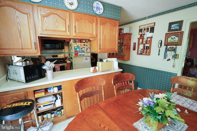 kitchen with kitchen peninsula, a textured ceiling, white fridge, and electric stove