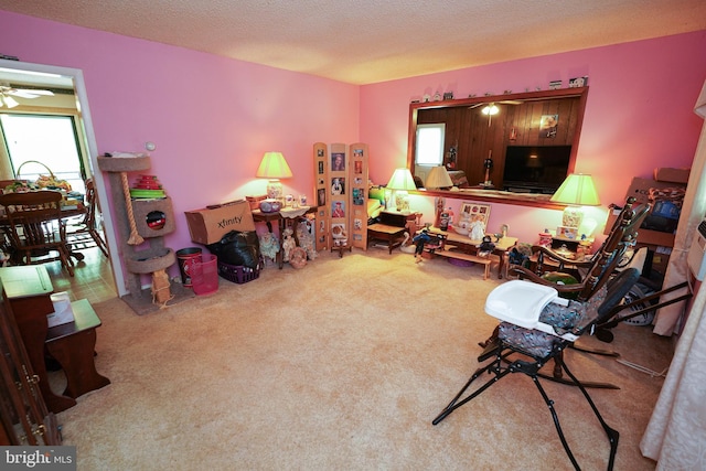 sitting room with ceiling fan, carpet floors, and a textured ceiling