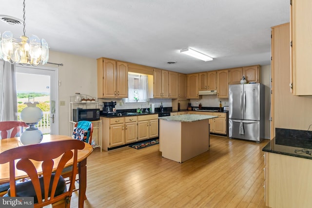 kitchen with appliances with stainless steel finishes, a center island, light brown cabinets, an inviting chandelier, and hanging light fixtures