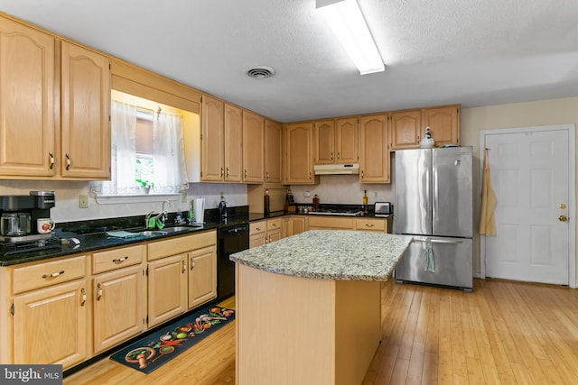 kitchen with a textured ceiling, a kitchen island, stainless steel appliances, sink, and light wood-type flooring